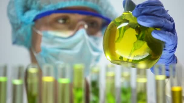 Wetenschapper markering kolf met plant bij het behoud van de gele vloeistof experimenteren resultaat - Video