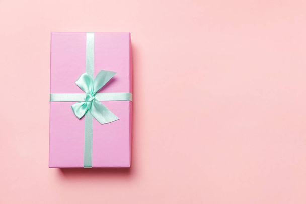 Christmas New Year birthday valentine celebration present romantic concept. Small gift box wrapped pink paper isolated on pink pastel colorful trendy background. Flat lay top view copy space - Photo, Image