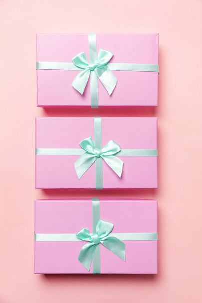 Boże Narodzenie nowy rok urodziny valentine obecny romantyczna koncepcja. Trzy małe pudełka zapakowane różowy papier na białym tle na tle różowej, pastelowe, kolorowy, modny. Miejsce płaskie świeckich widok z góry - Zdjęcie, obraz