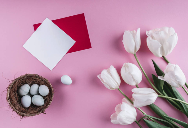 Ovos de Páscoa em ninho e flores de tulipa no fundo da primavera. Vista superior com espaço de cópia. Feliz cartão de Páscoa
. - Foto, Imagem