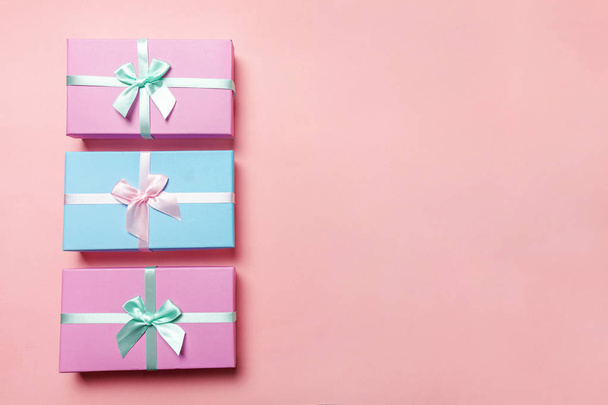 Kerstmis-Nieuwjaar Valentijn verjaardag romantische concept voorleggen. Drie geschenkdozen verpakt roze blauw papier geïsoleerd op roze pastel trendy kleurrijke achtergrond. Plat lag bovenaanzicht kopie ruimte - Foto, afbeelding