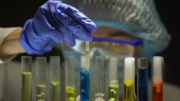 Wetenschapper meten van de zuurgraad niveau in buis met blauwe vloeistof in donker laboratorium - Video