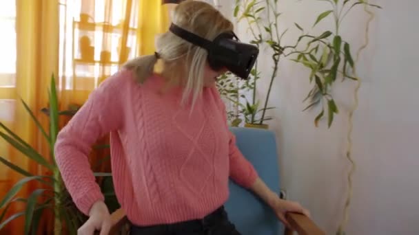 donna in maglione rosa a casa spaventata con occhiali di realtà virtuale in poltrona modernaGuardarsi intorno e usare gesti con le mani
 - Filmati, video