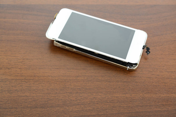 Kaputtes Smartphone auf dem Schreibtisch - Foto, Bild