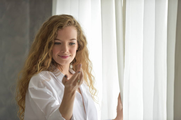 portrait d'une jeune femme belle et heureuse sexy L'acte des femmes Avec des gestes Quand elle se réveille Le matin, en pyjama blanc
. - Photo, image
