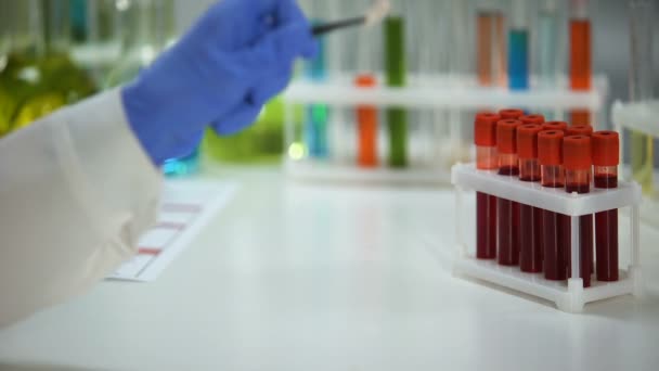 Trabajador de laboratorio médico sosteniendo cápsula, muestras de sangre en el fondo, productos farmacéuticos
 - Metraje, vídeo