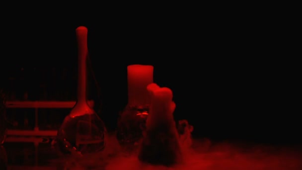 Sustancias químicas en frascos que burbujean y emiten humo bajo luz roja, laboratorio
 - Metraje, vídeo