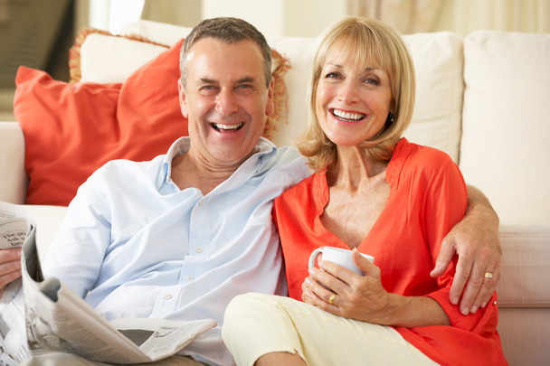 Senior Couple Relaxing On Sofa At Home Reading Newspaper - Foto, imagen