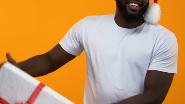 African young man white t-shirt holding big gift box, christmas sale, festivity - Кадри, відео