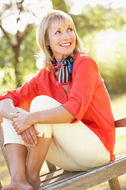 Senior Woman Sitting Outdoors On Bench - Foto, imagen