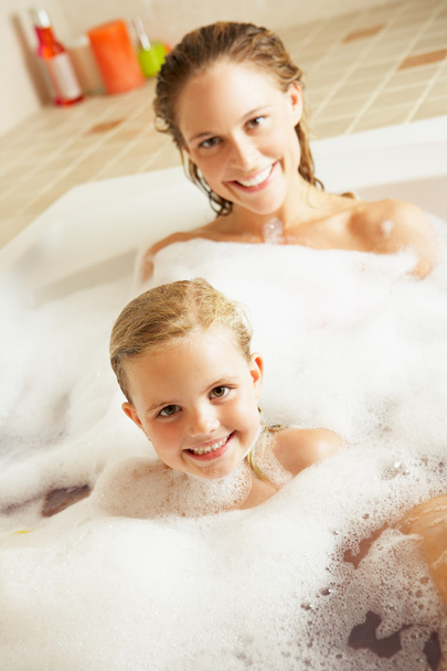 Mother And Daughter Relaxing In Bubble Filled Bath - Foto, afbeelding