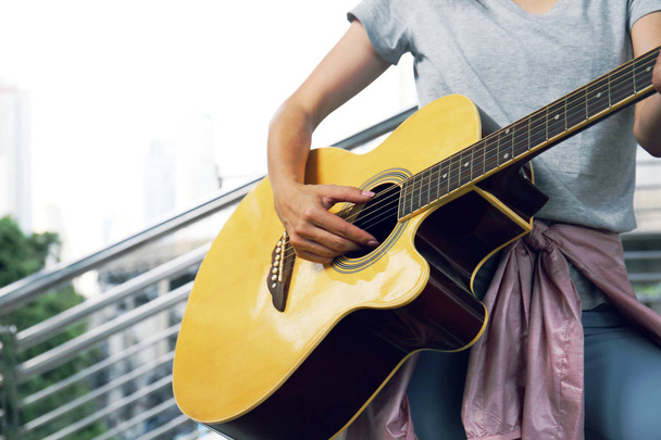 Крупним планом жінки грають на акустичній гітарі на вулиці
. - Фото, зображення