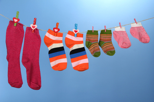 Colorful socks hanging on clothesline, on color background - 写真・画像