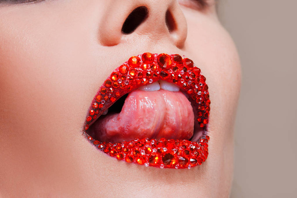 Red lips covered with rhinestones. Beautiful woman with red lipstick on her lips - Foto, imagen