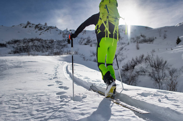 Escalador con esquí de montaña sube por una pista golpeada
. - Foto, imagen
