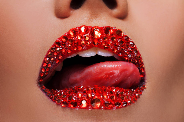 Red lips covered with rhinestones. Beautiful woman with red lipstick on her lips - Zdjęcie, obraz
