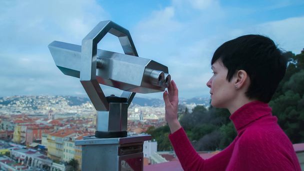 Woman tourist standing on the observation deck looking through a telescope. - Photo, Image