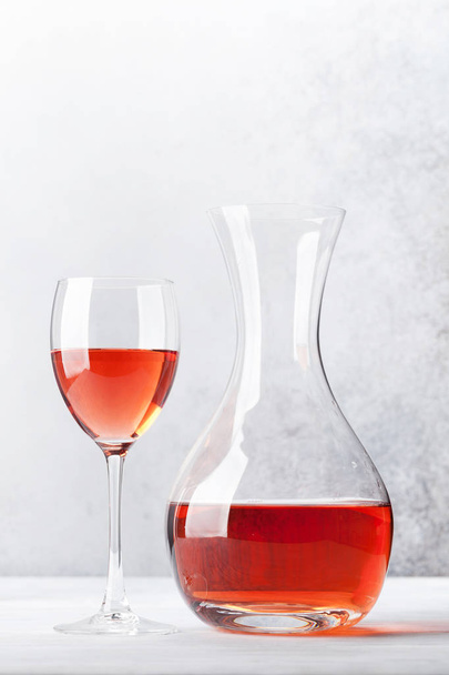 Rose wine in glass and decanter on wooden table. In front of stone wall with space for your text - Valokuva, kuva