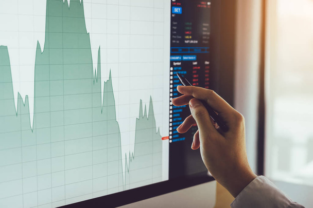 Крупный план руки бизнесмена, указывающий на график фондового рынка и анализ на экране компьютера
. - Фото, изображение