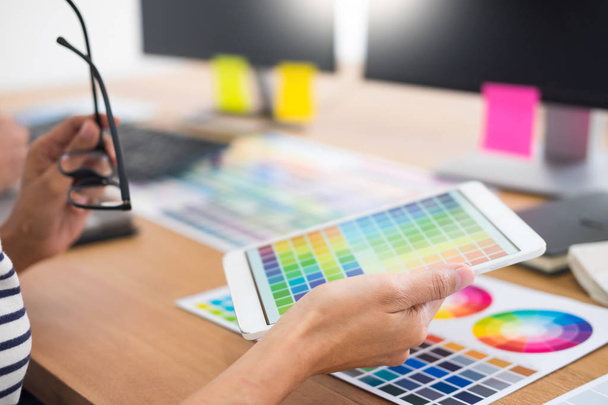 projektanta Edytor w pracy rysowania szkiców nowy projekt graficzny tablet i kolorów palety siedzi przy biurku z komputera w studio lub w biurze - Zdjęcie, obraz
