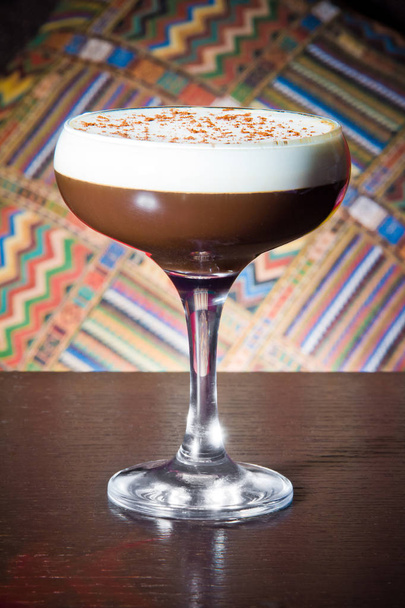 coffee alcoholic cocktail with crema and chocolate crumb on the background of the ethnic pattern on a wooden table - Foto, immagini