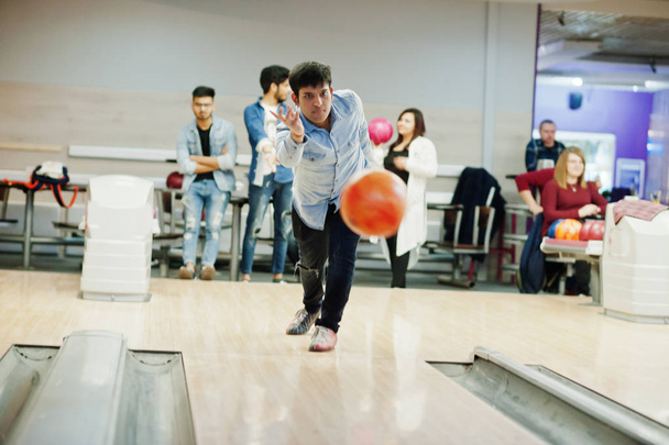 South asian man in jeans shirt standing at bowling alley and throw ball in air. - Foto, imagen