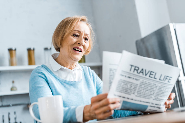 senior woman reading travel newspaper at home - Foto, afbeelding