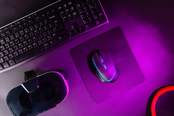von oben eine Spieleausrüstung, Maus, Tastatur, Steuerknüppel, Headset, vr Headset auf schwarzem Tischhintergrund. - Foto, Bild