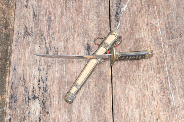 espada acero hoja samurai y vaina caballete antiguo en piso de madera antigua superficie con espacio de copia
 - Foto, imagen