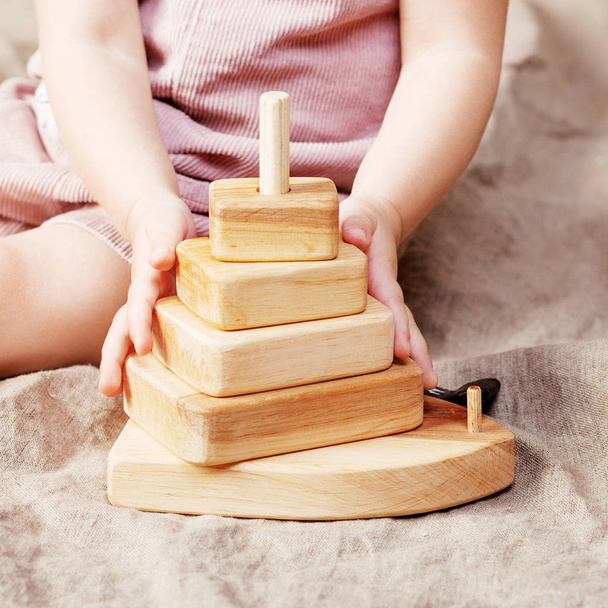 Child girl playing with a wooden toy pyramid. Little cute girl with  natural toys.  Close up picture - Valokuva, kuva