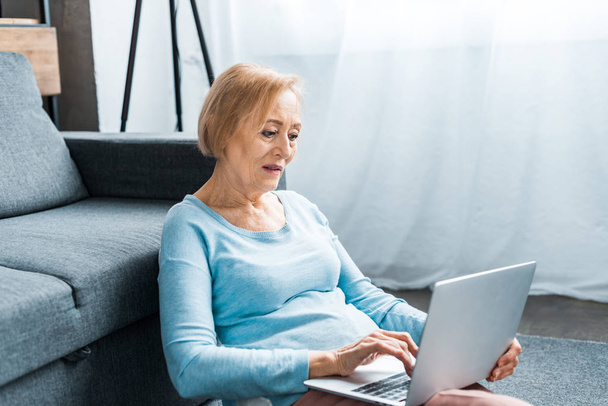 donna anziana seduta e digitando sul computer portatile a casa
 - Foto, immagini