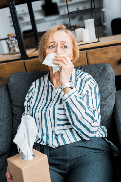 sick senior woman with runny nose holding tissue and suffering from cold at home - Foto, Bild
