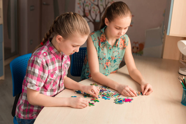 Two little girls solving puzzle together sitting at the table - Foto, Bild