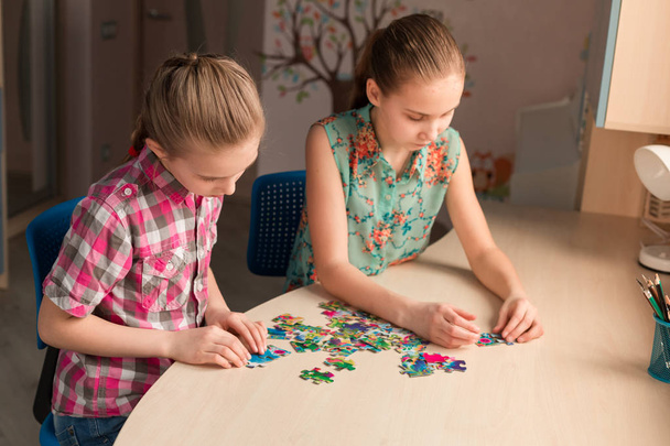 Two little girls solving puzzle together sitting at the table - Foto, Bild