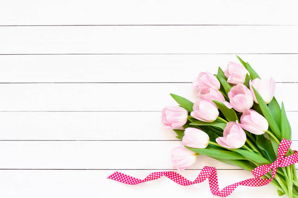 Bouquet of pink tulips decorated with ribbon on white background. Top view, copy space. Flat lay of Valentines Day, Mothers Day, birthday celebration concept. - Fotografie, Obrázek