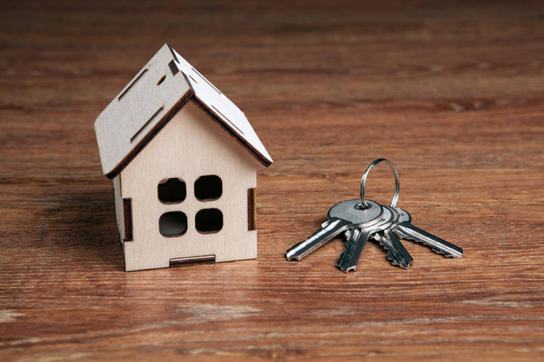 wooden miniature house and a door key on a wooden background close up - Photo, Image