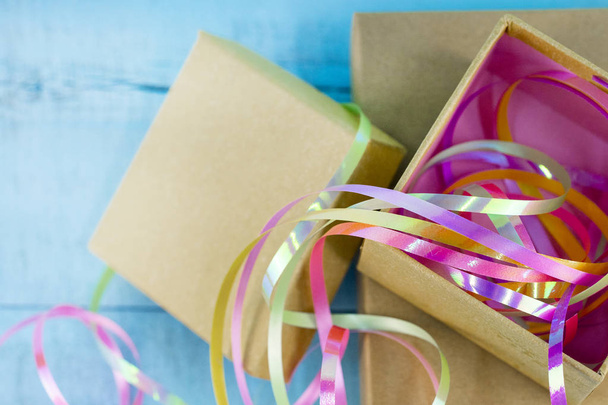 cinta de embalaje brillante de diferentes colores con caja de regalo sobre fondo de madera azul
 - Foto, Imagen