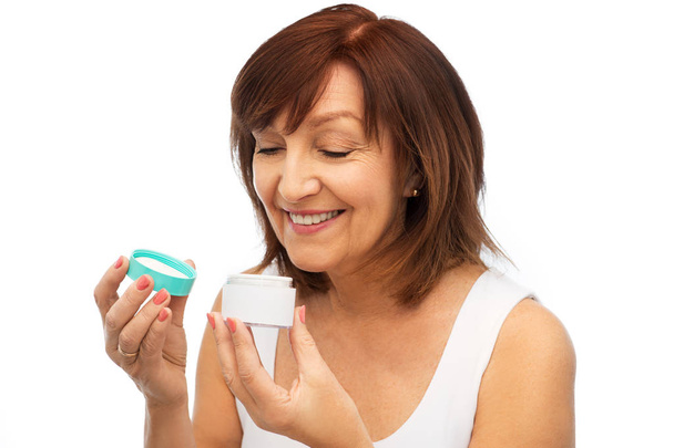 smiling senior woman with cream jar - Foto, Imagen