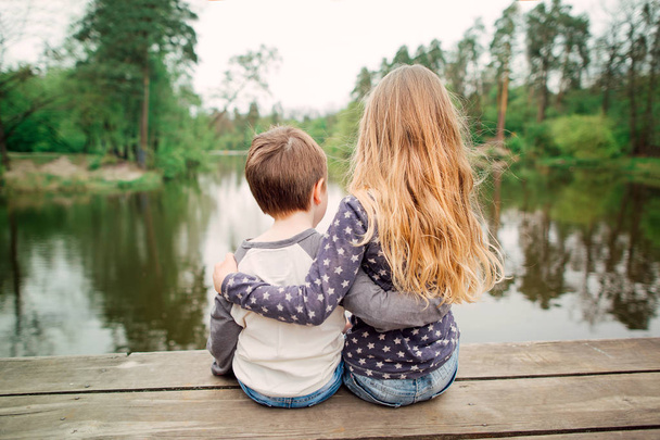 Sorella e fratello seduti e godendo sul ponte di legno
 - Foto, immagini