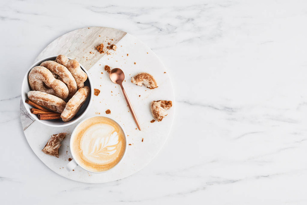 Café ou cappuccino com arte latte e biscoitos de gengibre em mármore branco servindo placa sobre fundo de mármore. Conceito de pequeno almoço. Vista superior com espaço de cópia para texto
. - Foto, Imagem