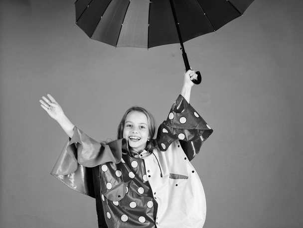 Enjoy rainy weather with proper garments. Waterproof accessories for children. Waterproof accessories make rainy day cheerful and pleasant. Kid girl happy hold colorful umbrella wear waterproof cloak - Foto, Imagen