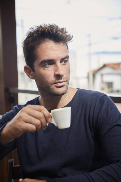 Handsome guy with coffee in cafe, looking away - 写真・画像