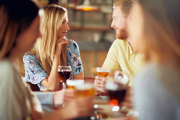 Amigos charlando y bebiendo alcohol mientras están sentados en el restaurante
. - Foto, imagen