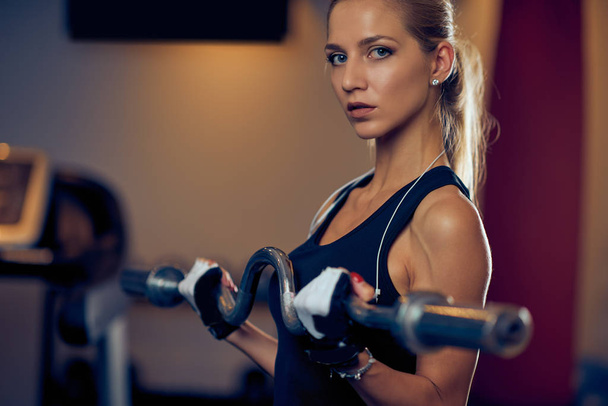 Close up of woman lifting weight bar. Gym interior. Healthy lifestyle concept. - Foto, Imagem