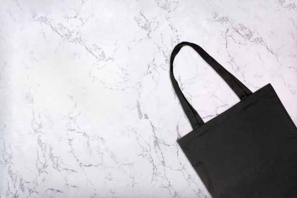 白の大理石テクスチャを黒のトートバッグのクローズ アップ。大理石の背景に空白の再利用可能なショッピング バッグです。トップ ビュー - 写真・画像