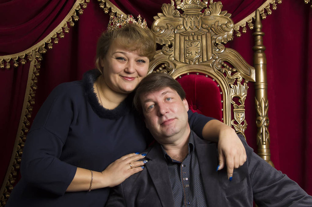 Σύζυγος και η σύζυγος σε μια όμορφη καρέκλα. Ο άντρας είναι ο βασιλιάς βασίλισσα γυναίκα. Μεσήλικες ζευγάρι - Φωτογραφία, εικόνα