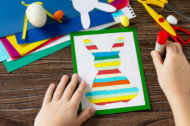 Het kind lijm details een paashaas voor Pasen briefkaart. Handgemaakte. Project voor kinderen van creativiteit, ambachten, handwerk voor kinderen. - Foto, afbeelding