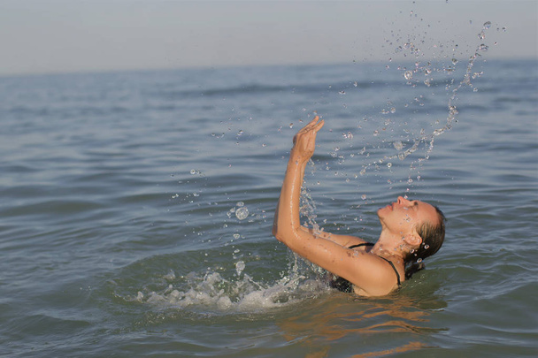 Mujer mayor en el mar con salpicaduras de agua
. - Foto, imagen