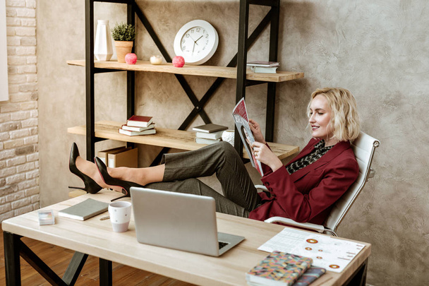 unprofessionelle kurzhaarige Frau, die ihre Beine auf den Bürotisch legt - Foto, Bild