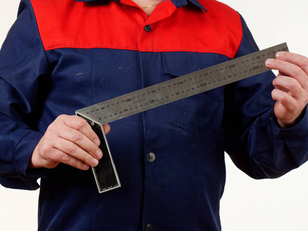 hombre en ropa de trabajo sosteniendo una herramienta cuadrada sobre fondo blanco 5
 - Foto, Imagen